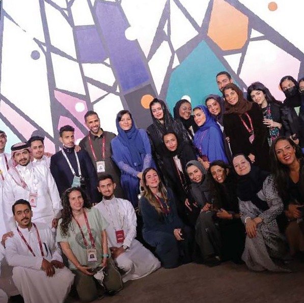 فريق الموقع مجتمعاً أمام عمل فني بعد الفعالية